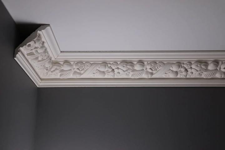 Enriched cornice returning around a corner against a dark wall